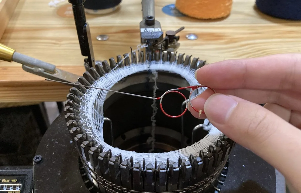 靴下編み機の針に糸をかける手元